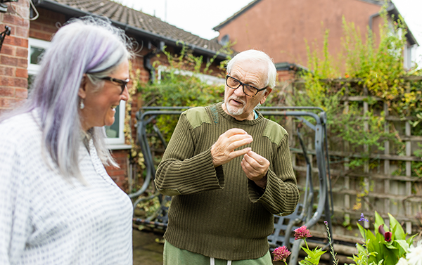 Two elderly people talking in a garden